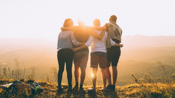 Four people with arms around each other looking over a vista