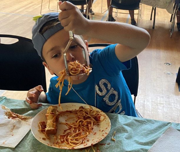 Boy eating spaghetti with a potato masher