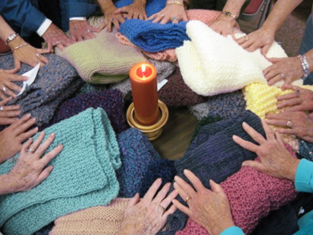 Hands splayed on a collection of prayer shawls