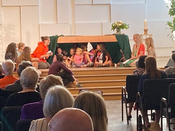 Ministers talking to children sitting under the chancel Table