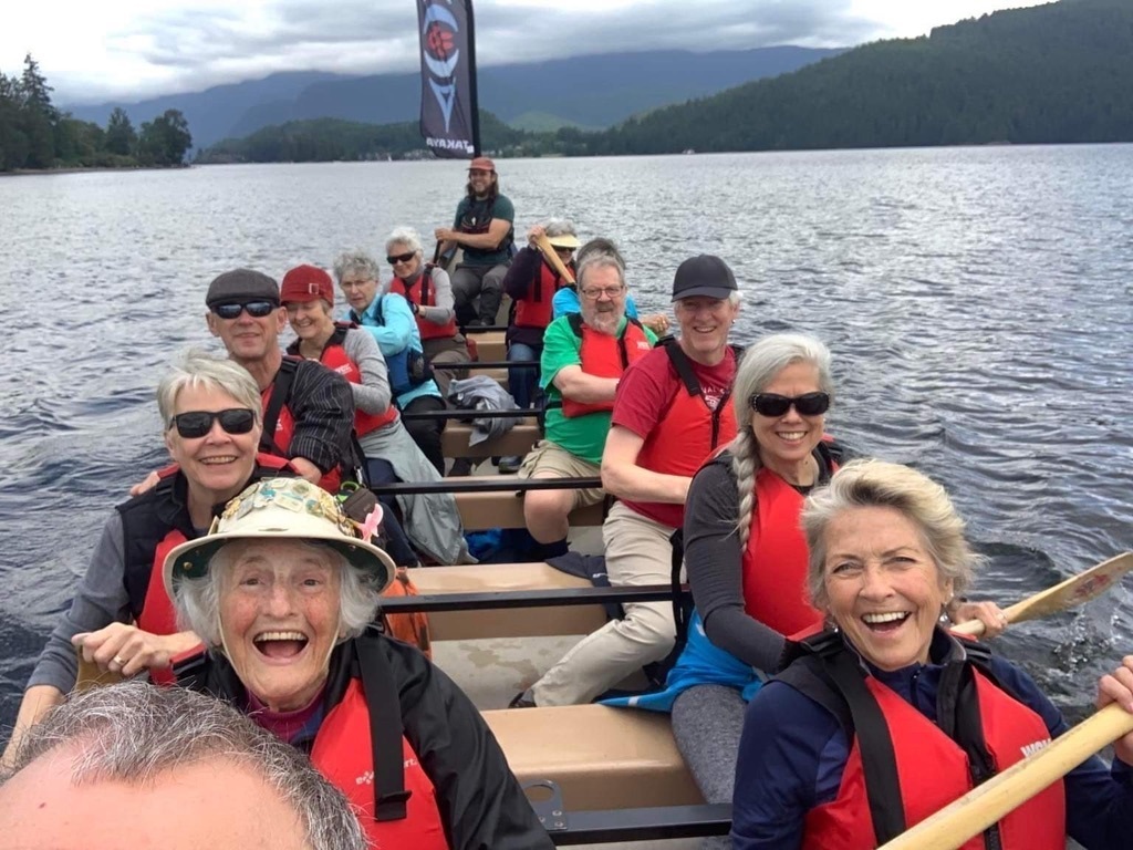 Members of the congregations in red life jackets in a canoe on a body of water