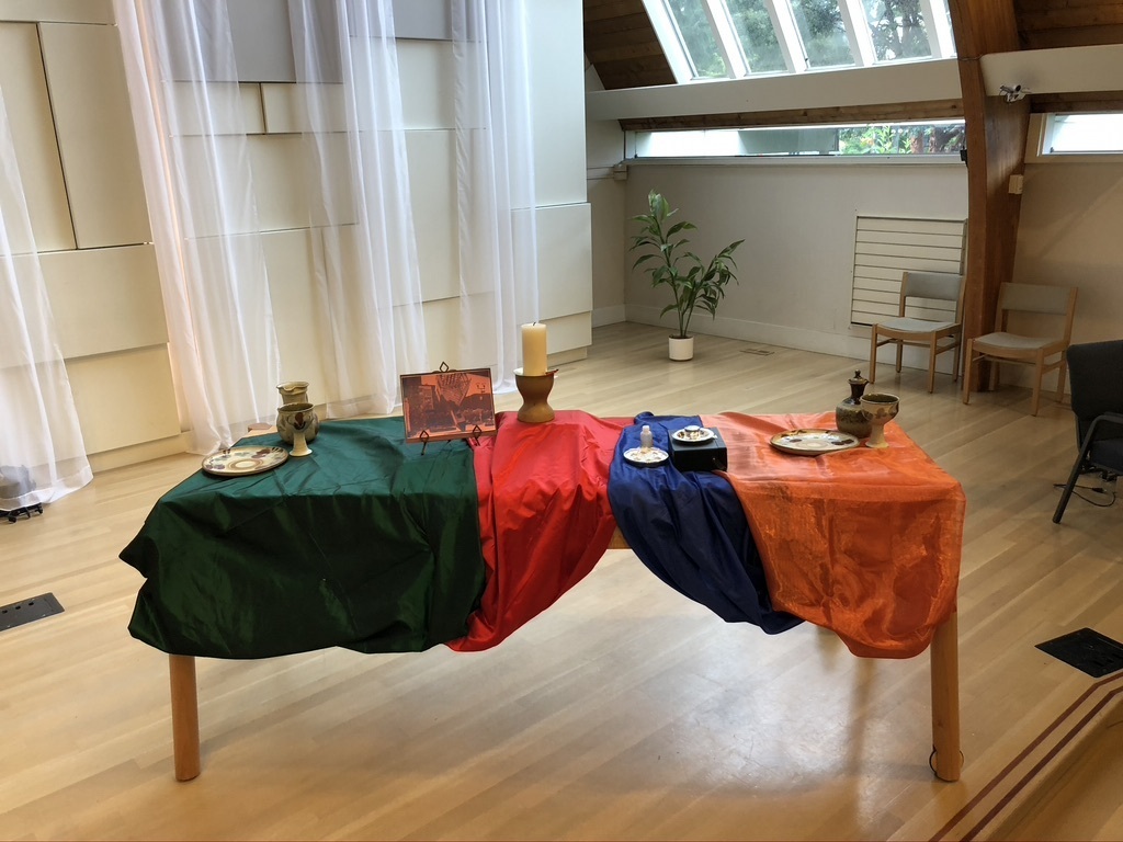 A communion table on the sanctuary stage with multicolour tablecloths